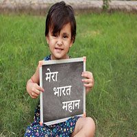 Happy cute Indian baby girl sitting in the park and holding writing slate in  hand and she showing it to the camera